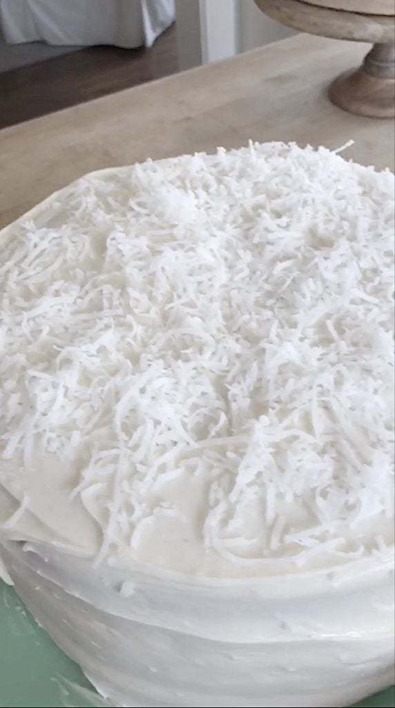 adding coconut to a frosted cake