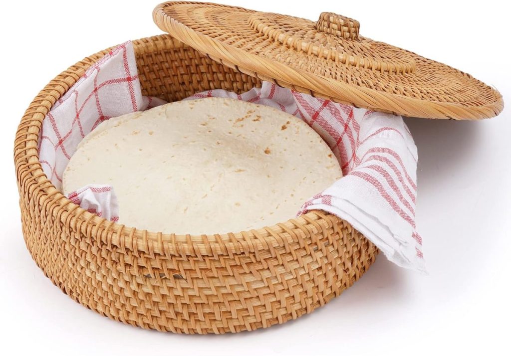 A stack of tortillas sits inside a round woven basket lined with a white and red striped cloth, the basket lid partially open—perfect for a happy Taco Tuesday.