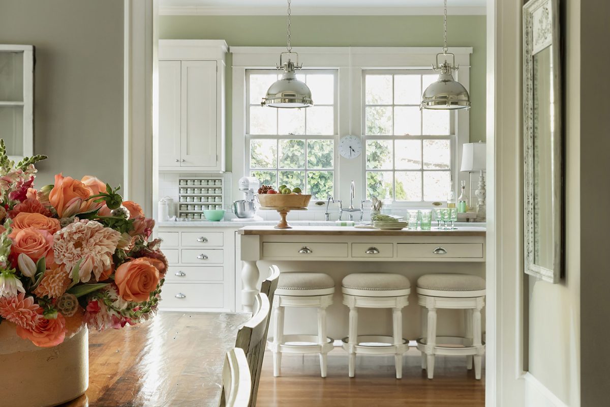 white kitchen with island and table with orange flowers