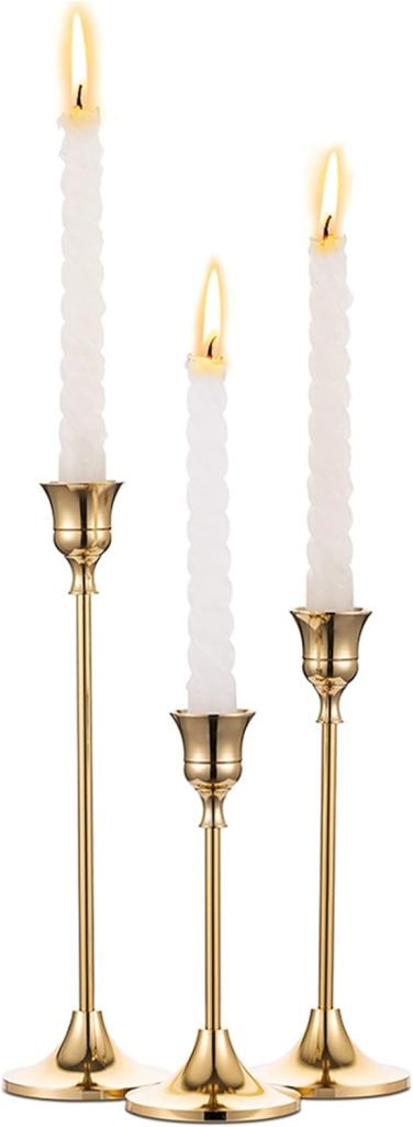 Three lit white spiral candles in gold holders of varying heights create a warm and elegant centerpiece, perfect for your Christmas dinner table.