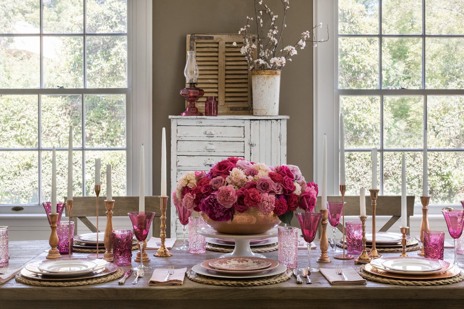 table in dining room with pink flowers, glasses, and plates
