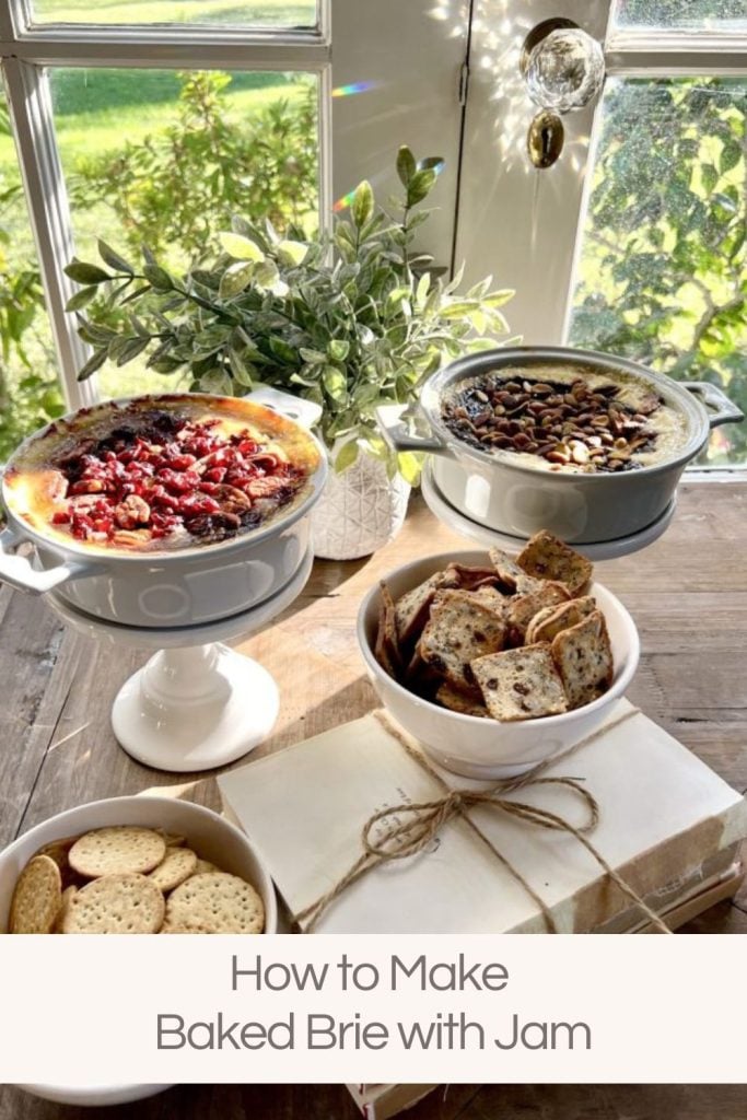 Two baked brie appetizers on small cake stands with two small bowls of crackers, one on top of a stack of books tied with twine.