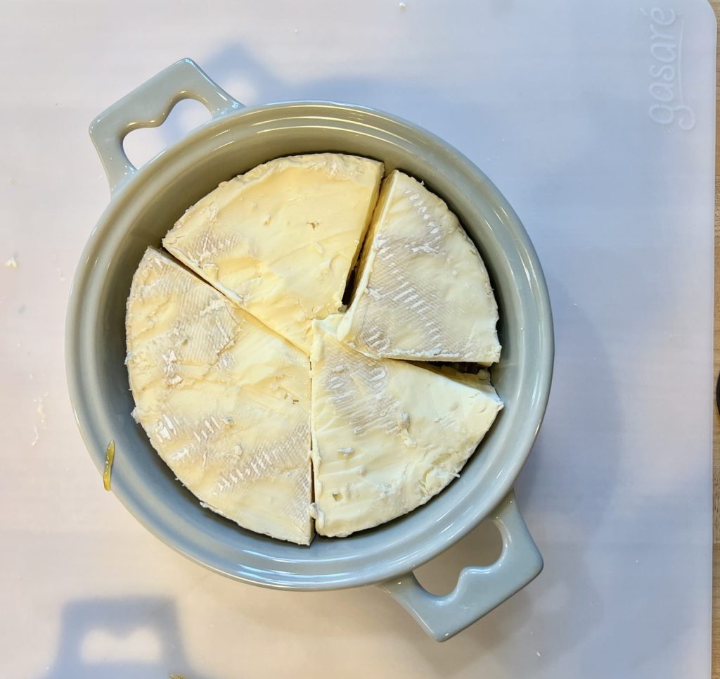 Overhead photo of brie cut in triangles to fit into a brie baking dish