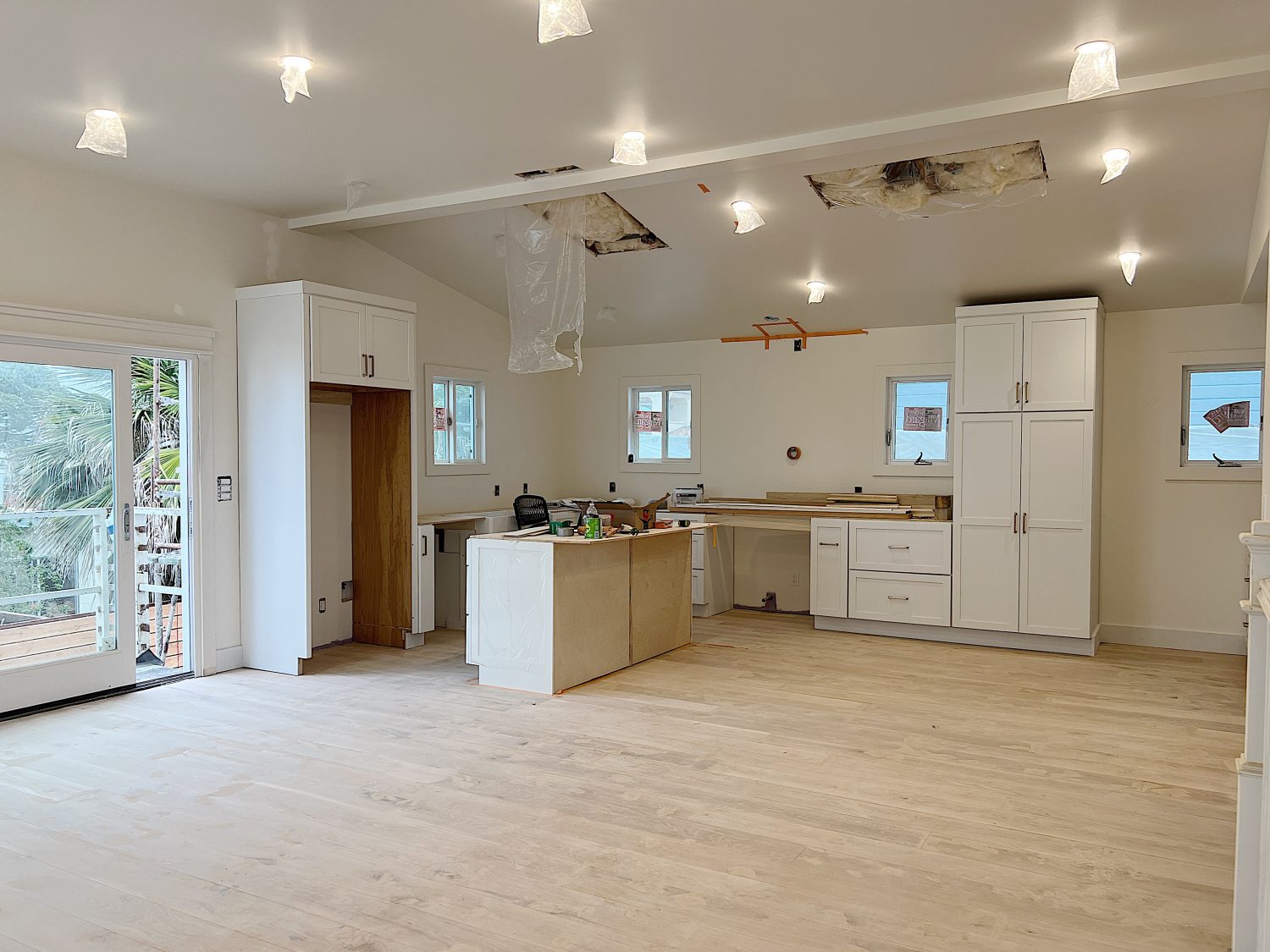 Beach house kitchen under construction with cabinets, island, and new wood flooring