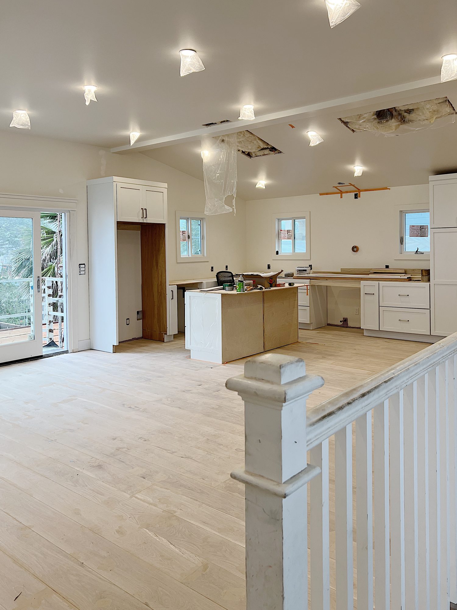 Beach house kitchen under construction with cabinets, island, and new wood flooring