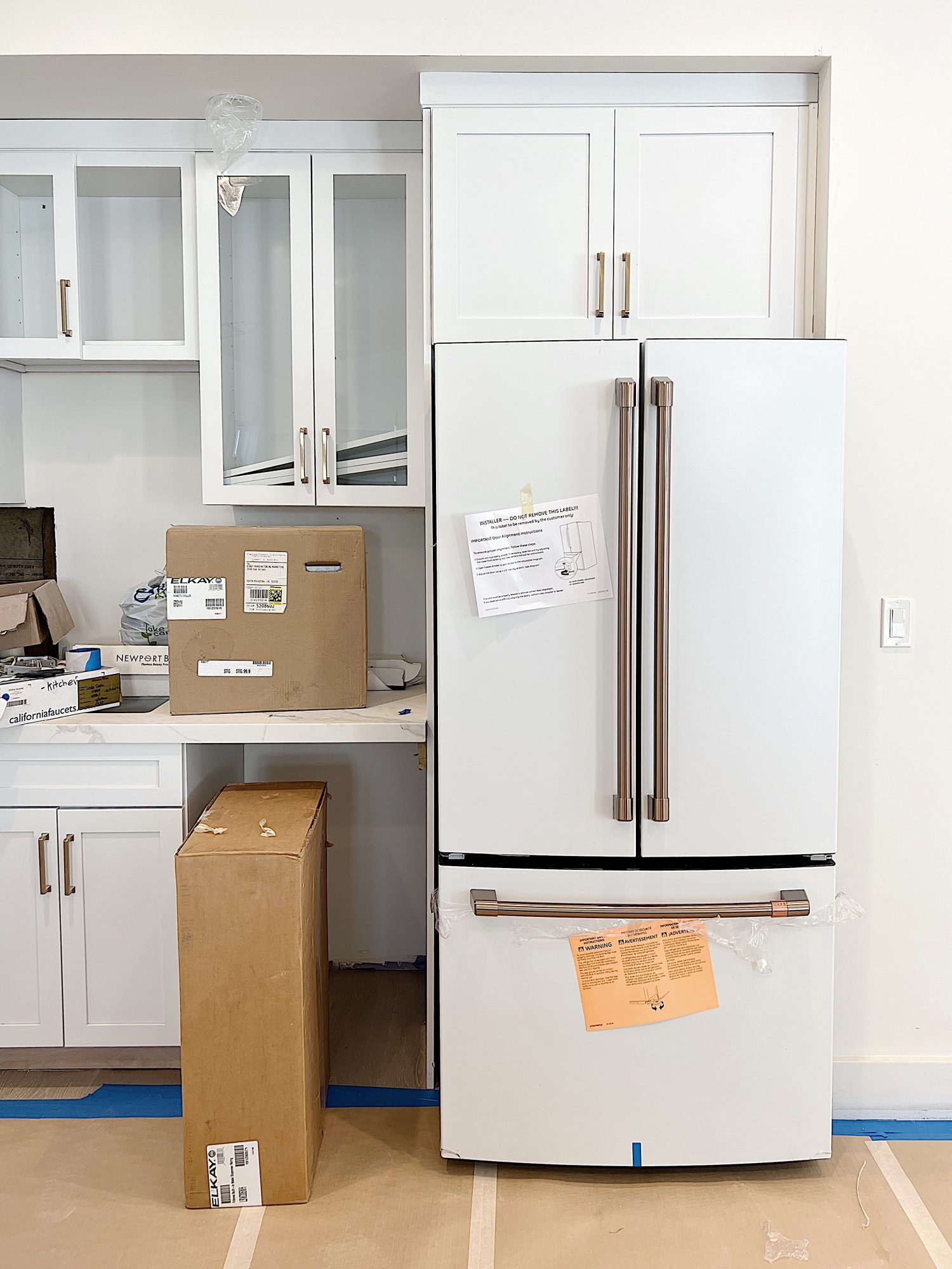 white kitcehn with new refrigerator not quite installed