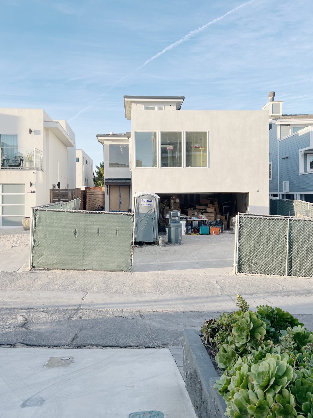 new beach house with white plaster exterior, windows and this floor deck