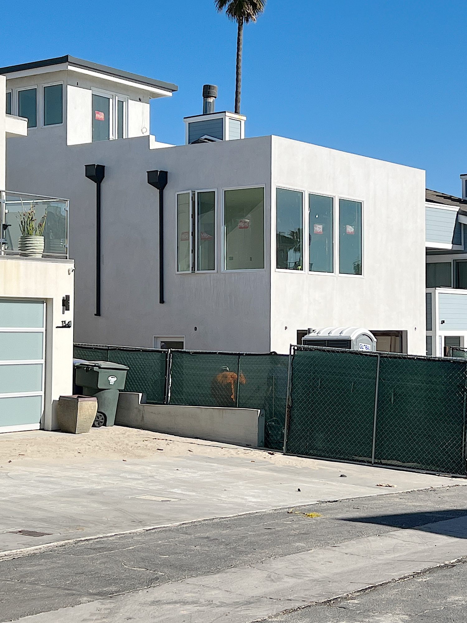 new beach house with white plaster exterior, windows and this floor deck