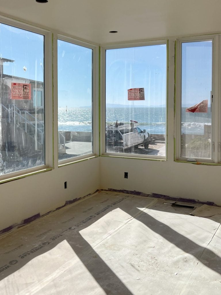view of the ocean looking through the windows in the primary suite bedroom on the beach house tour