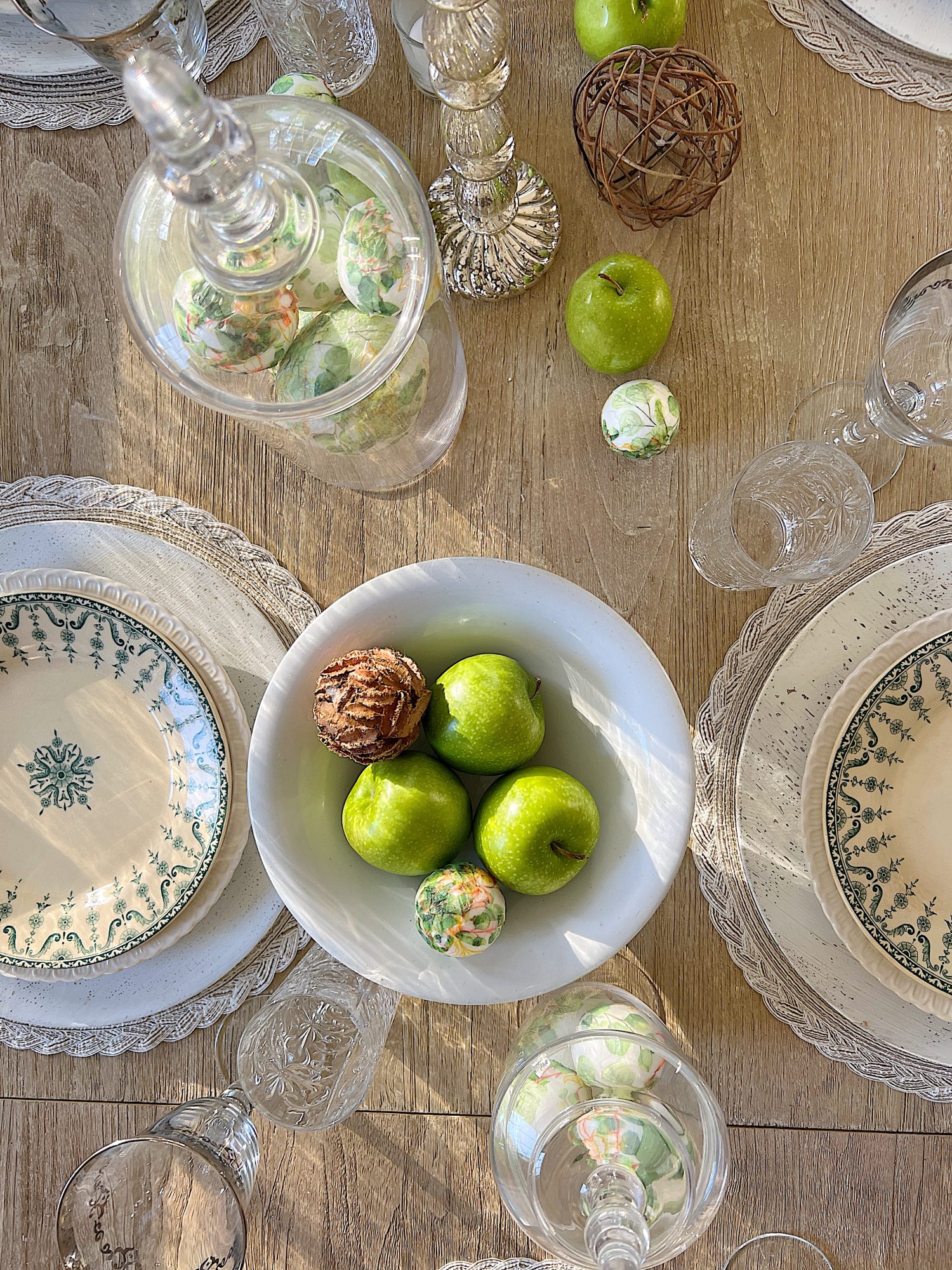 table with green palce settings decorated with green apples, wood balls, and decor balls
