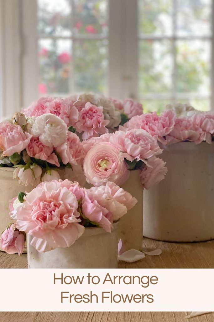 three crocks filled with pink flowers on a table