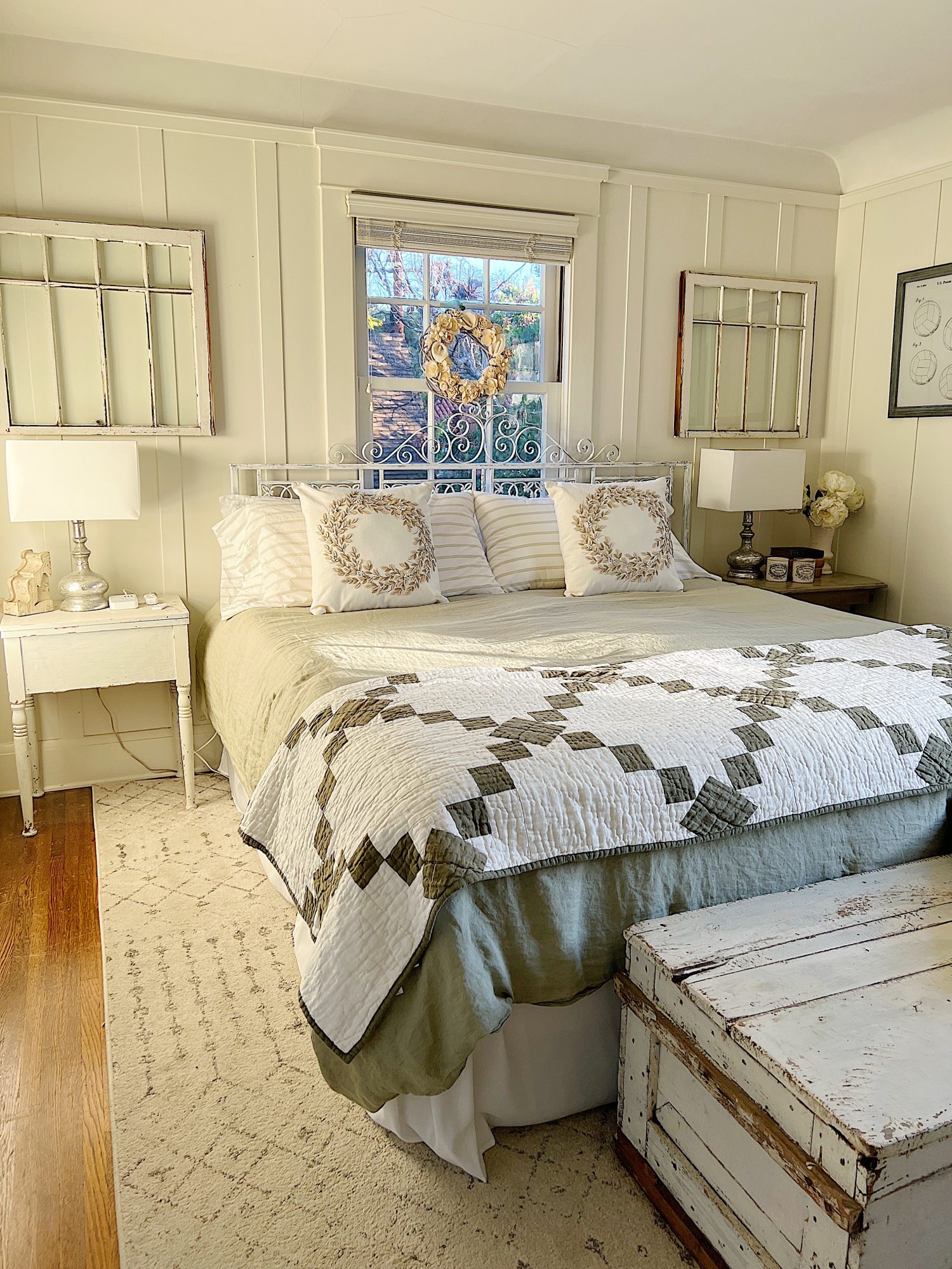 small bedroom with green linen duvet, green and white patchwork quilt, pillows and a nightstand on each side.