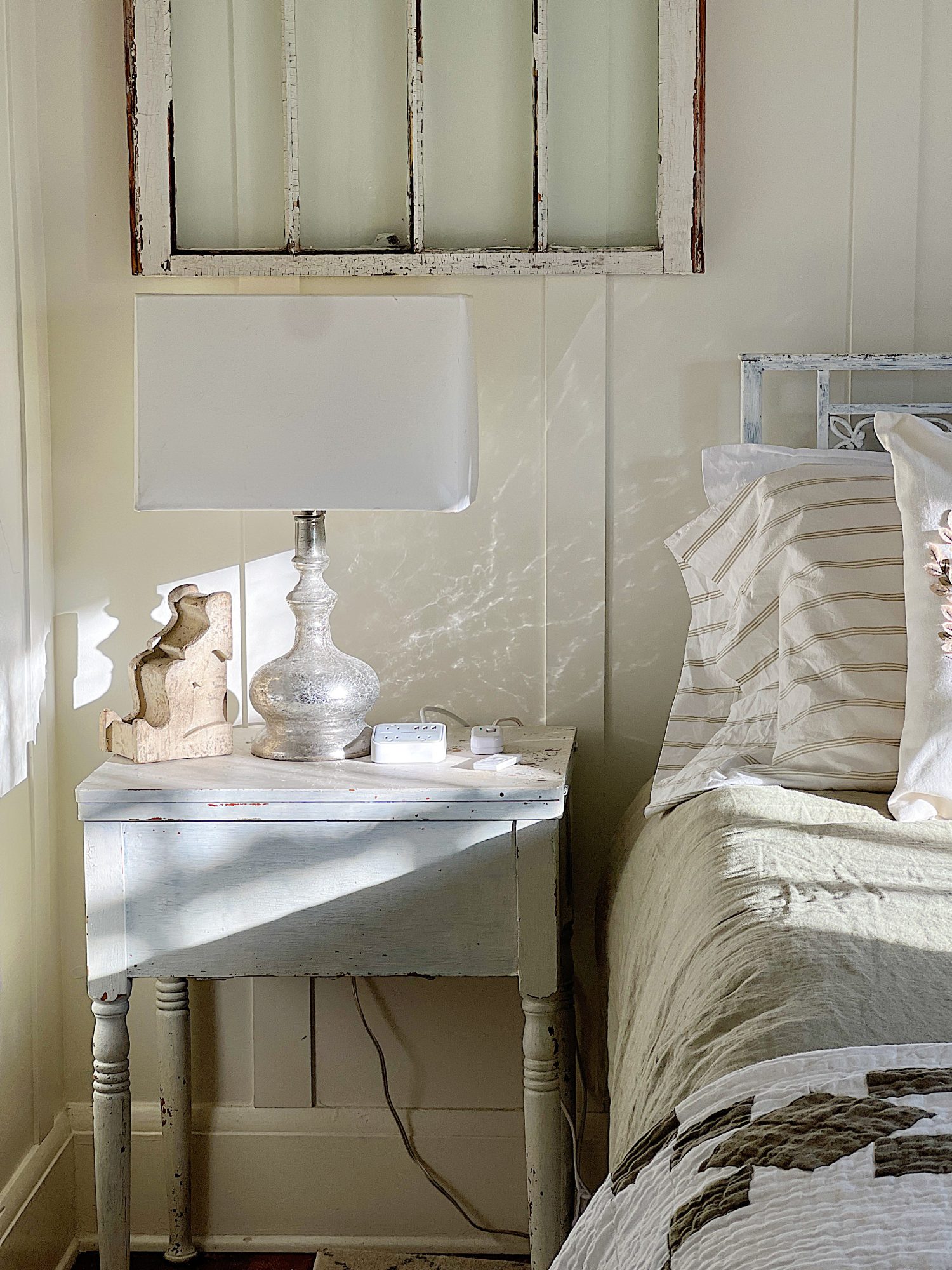 small bedroom with green linen duvet, green and white patchwork quilt, pillows and a nightstand on each side.