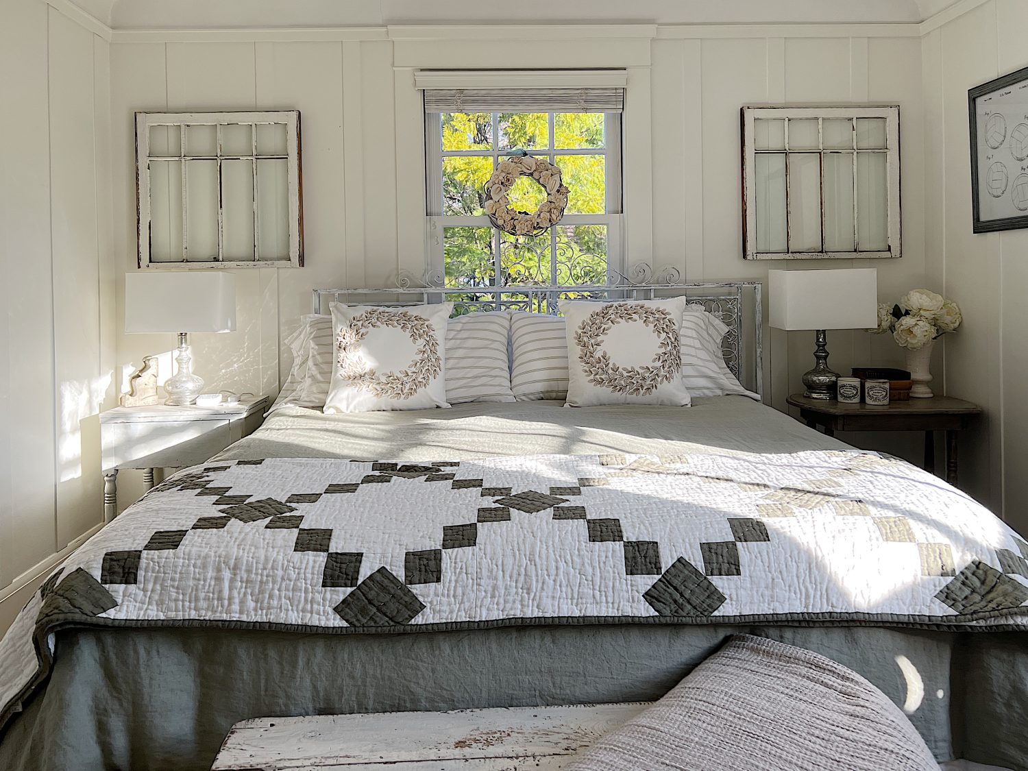 small bedroom with green linen duvet, green and white patchwork quilt, pillows and a nightstand on each side.