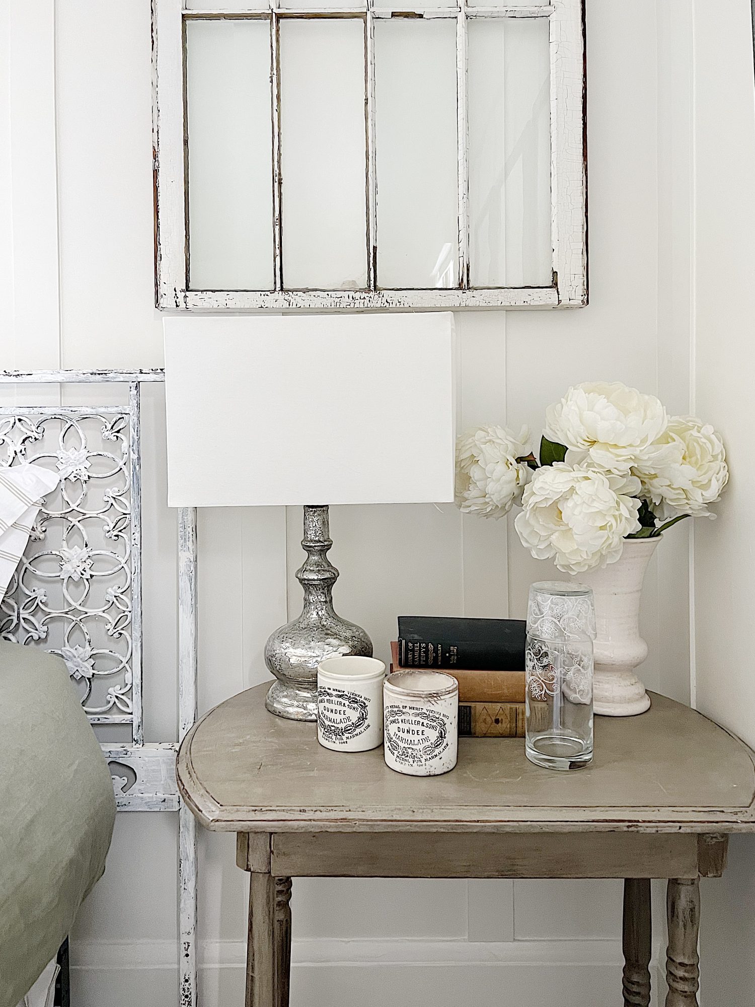 small bedroom with green linen duvet, green and white patchwork quilt, pillows and a nightstand on each side.