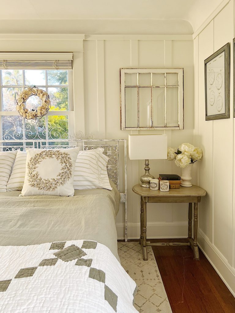 small bedroom with green linen duvet, green and white patchwork quilt, pillows and a nightstand on each side.