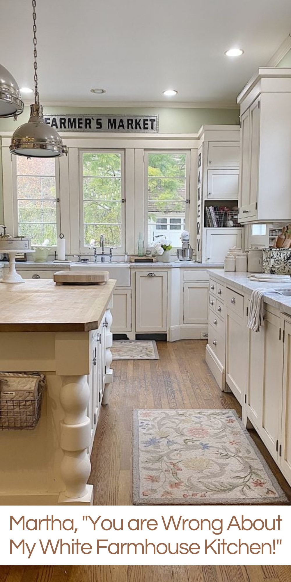 a white kitchen with windows and an island with a vase with white flowers, and a cutting board