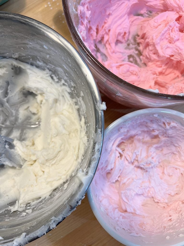 white, light pink, and pink buttercream frosting in bowls
