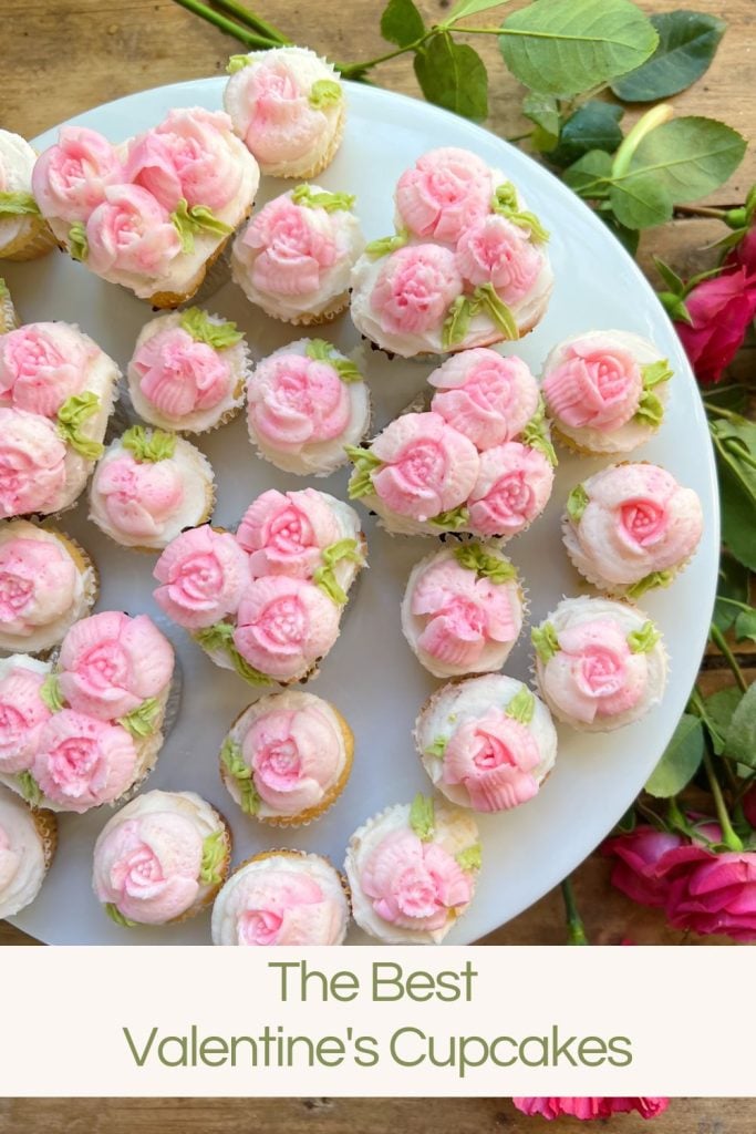 cupcakes decorated with white and pink buttercream frosting on a tray