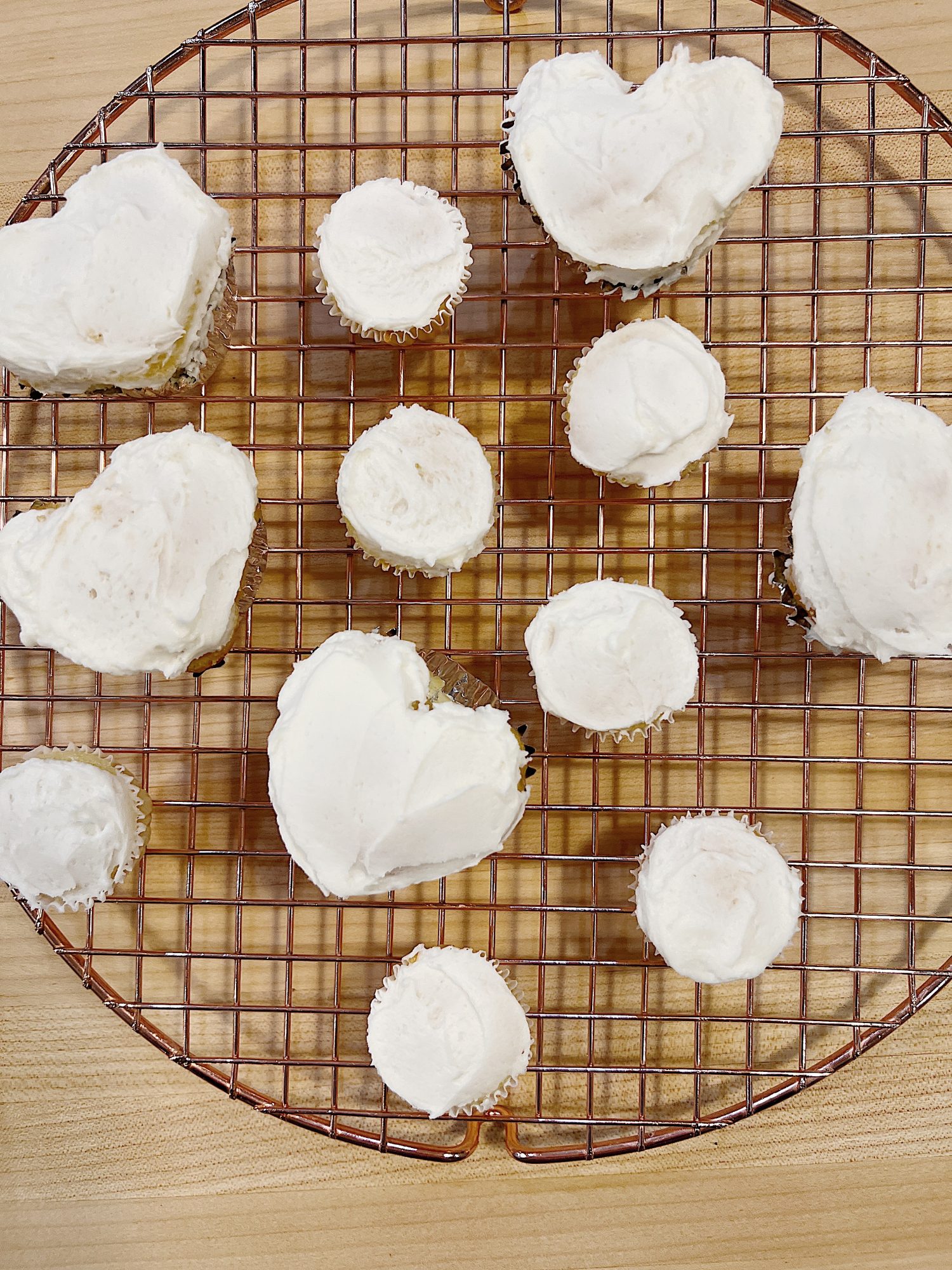 cupcakes frosted with white icing on a copper wire tray