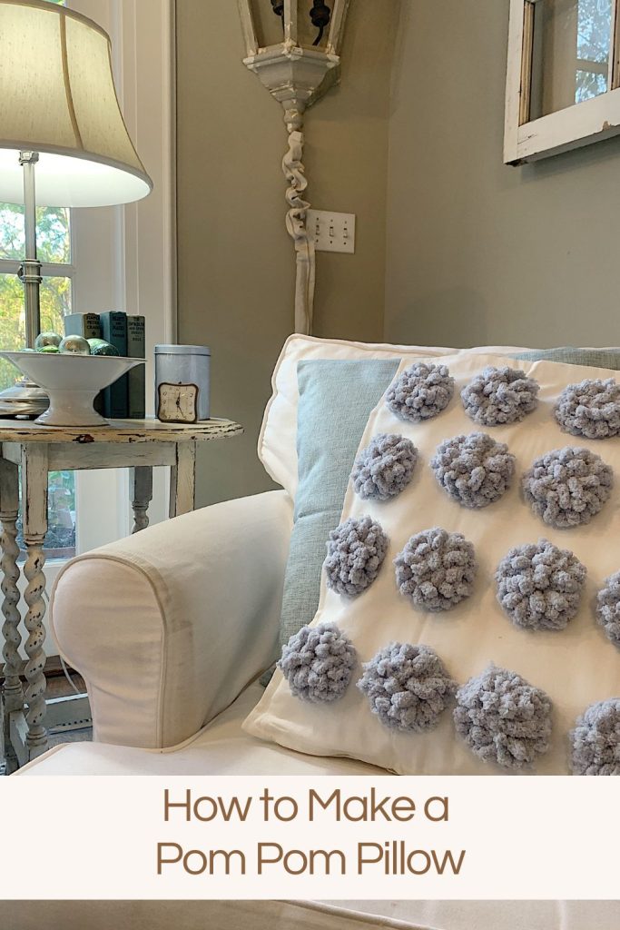 DIY white pillow with blue pom poms attached to the front