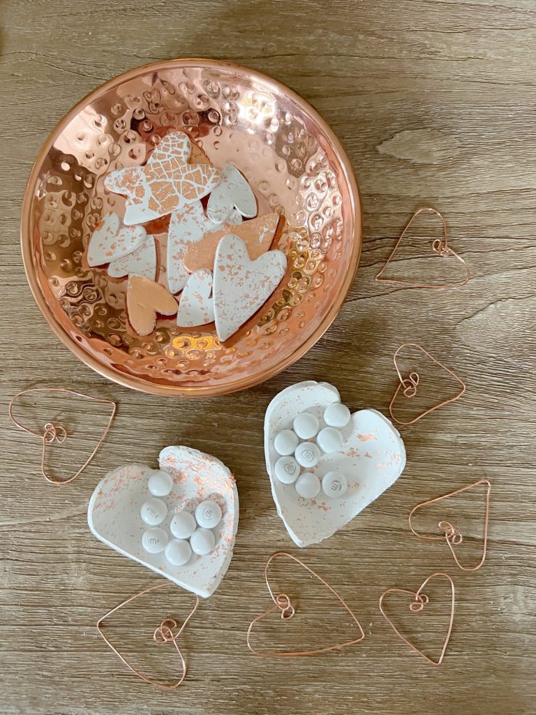 white clay and copper hearts molded into small candy dishes, hearts made from copper wire, and white clay hearts with copper foil cut into hearts.