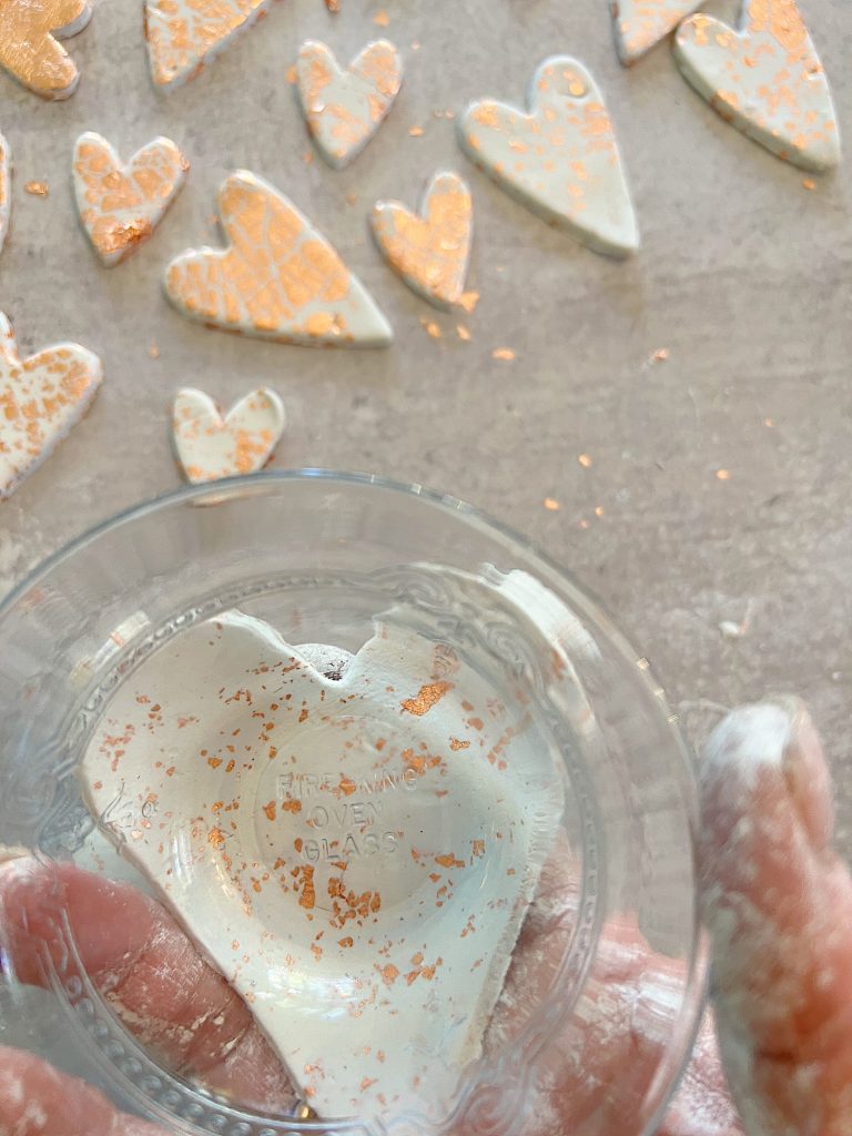 white clay hearts made from air dry clay, copper foil and a heart shaped cookie cutter placed on a glass bowl