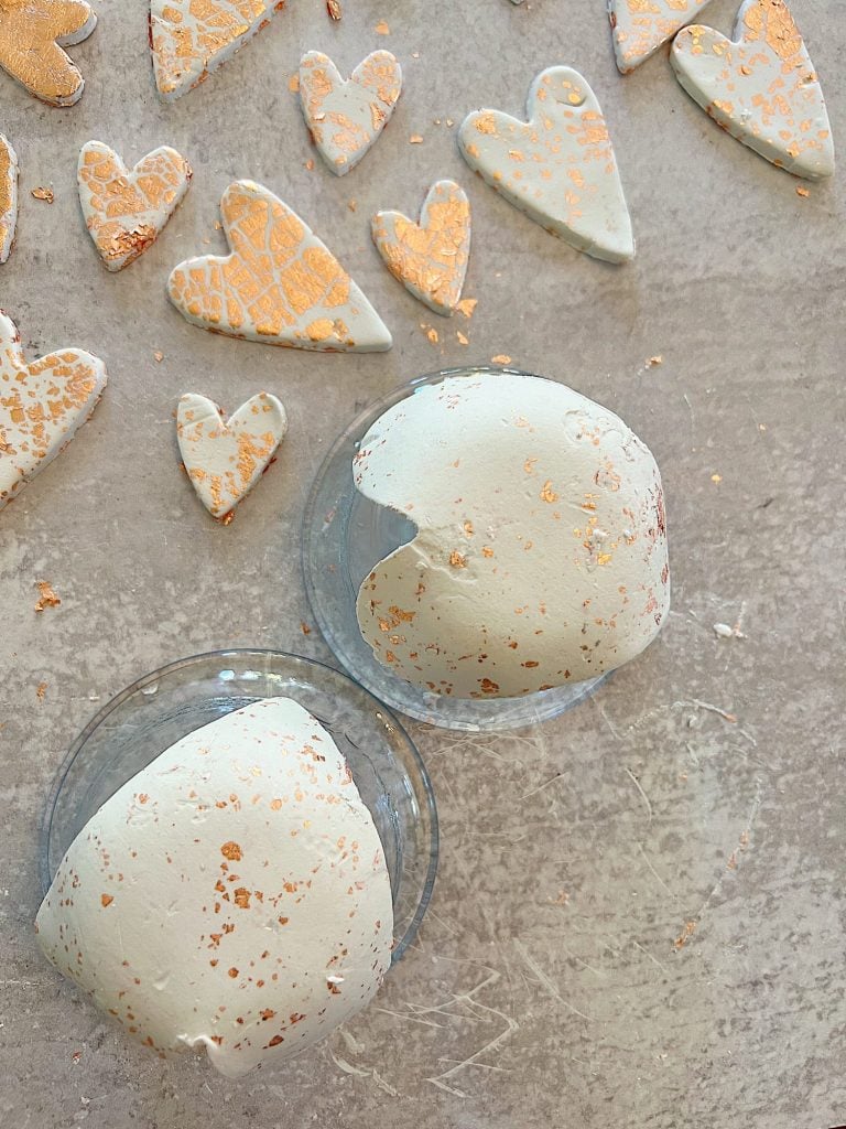 white clay hearts made from air dry clay, copper foil and a heart shaped cookie cutter placed on a glass bowl