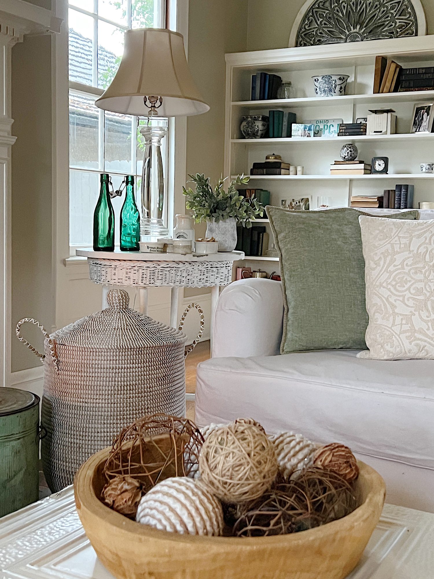 living room with white couch, green and winter pillows, talbe with decor and bookshelves