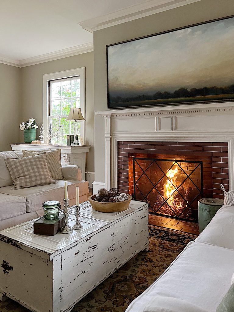 living room with white coach, white coffee table, decor and fire in the fireplace