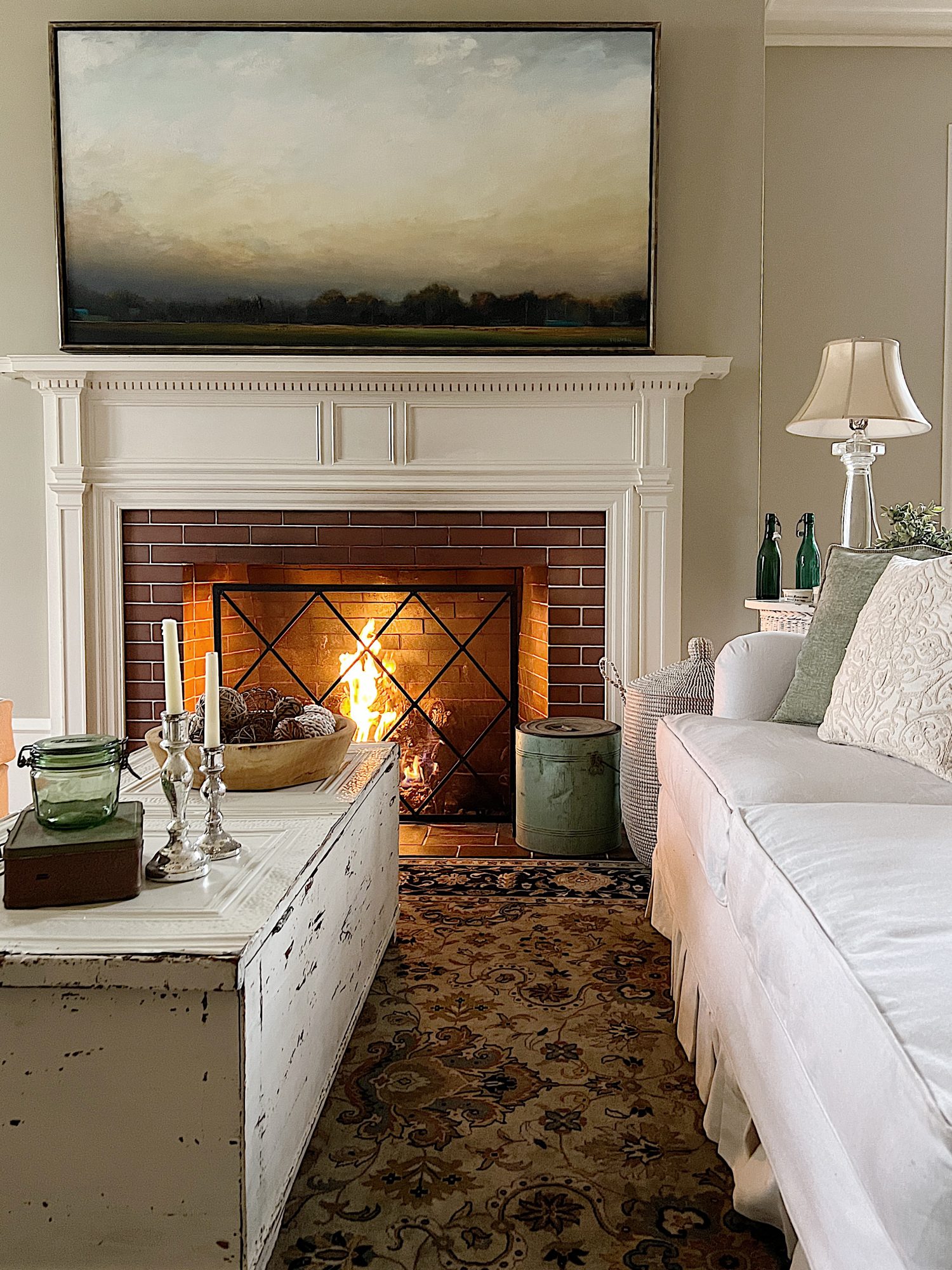 living room with white coach, white coffee table, decor and fire in the fireplace