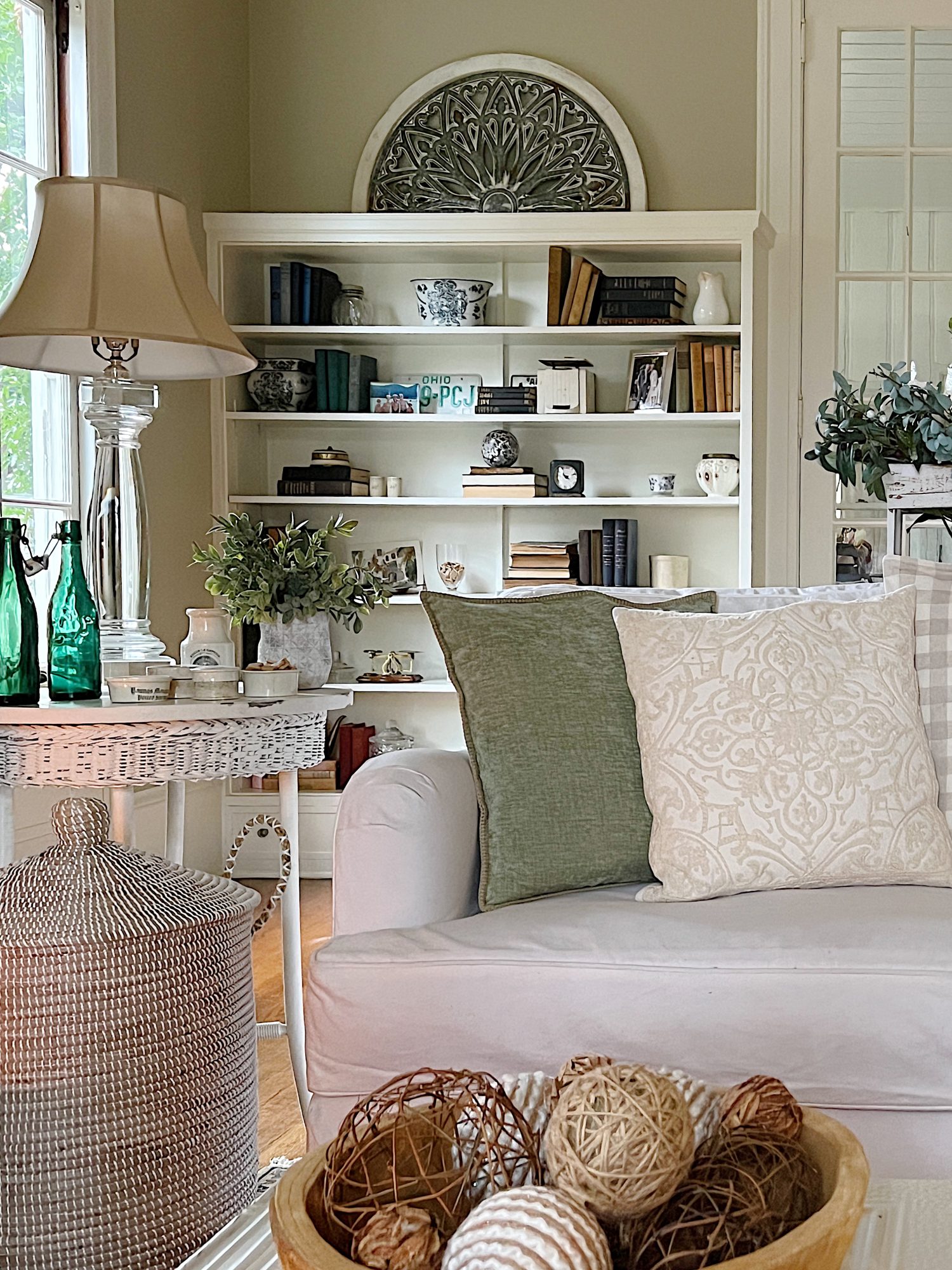 living room with white couch, green and winter pillows, talbe with decor and bookshelves