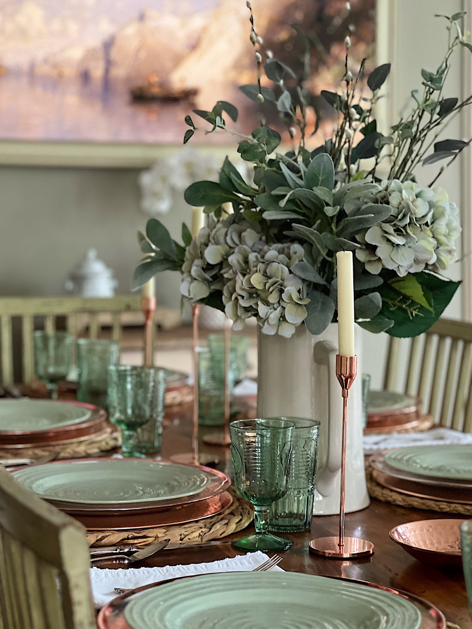 table set with hyacinth placemat, copper charger, green plate, green glasses, copper candlesticks, and green flowers in a vase