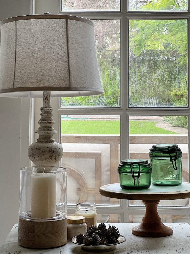 end table with lamp, green jars and candle.