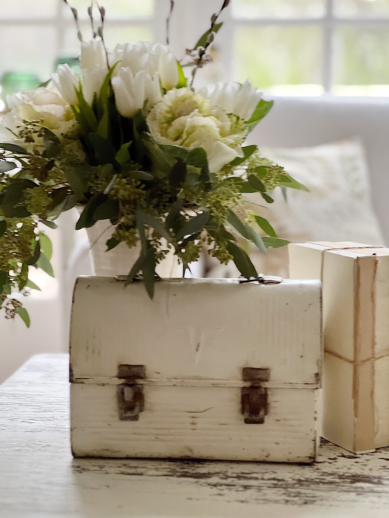 Coffee table with vintage shite lunch box, books, and flowers on top.