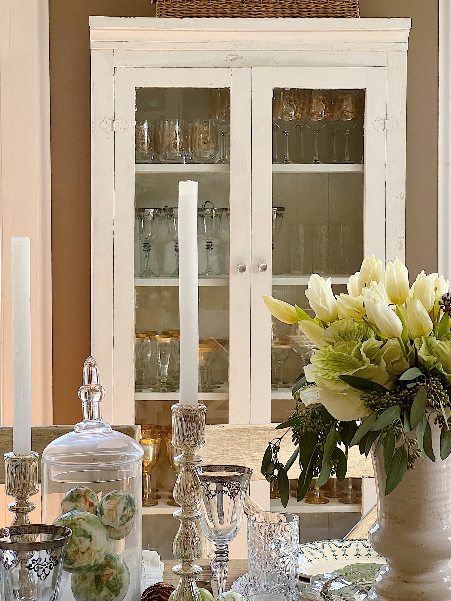 table with green palce settings and apothecary jars with green apples, wood balls, silver goblets, and decor balls