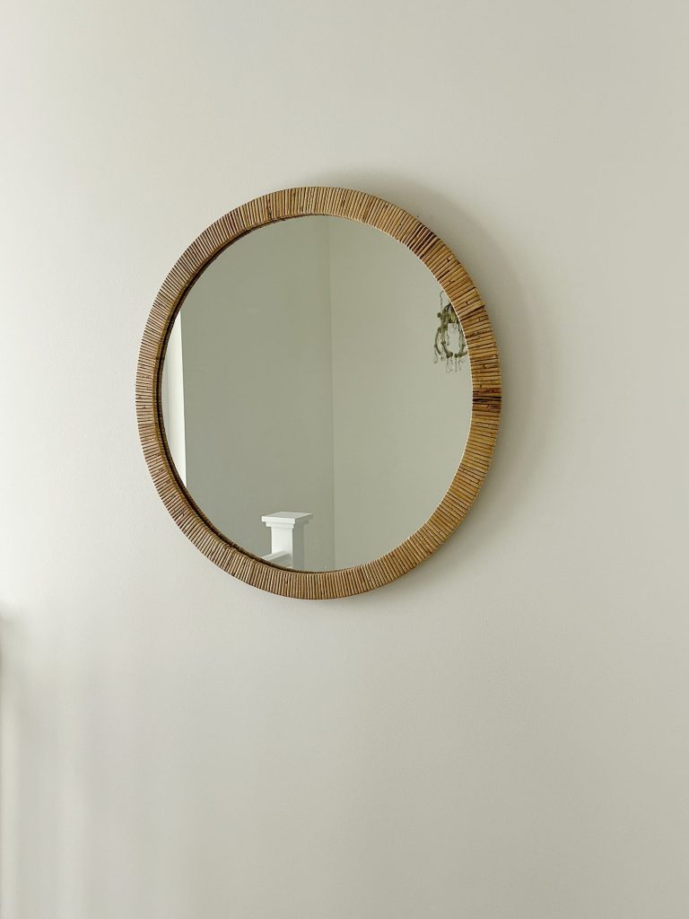 Rattan round mirror hanging on white wall.