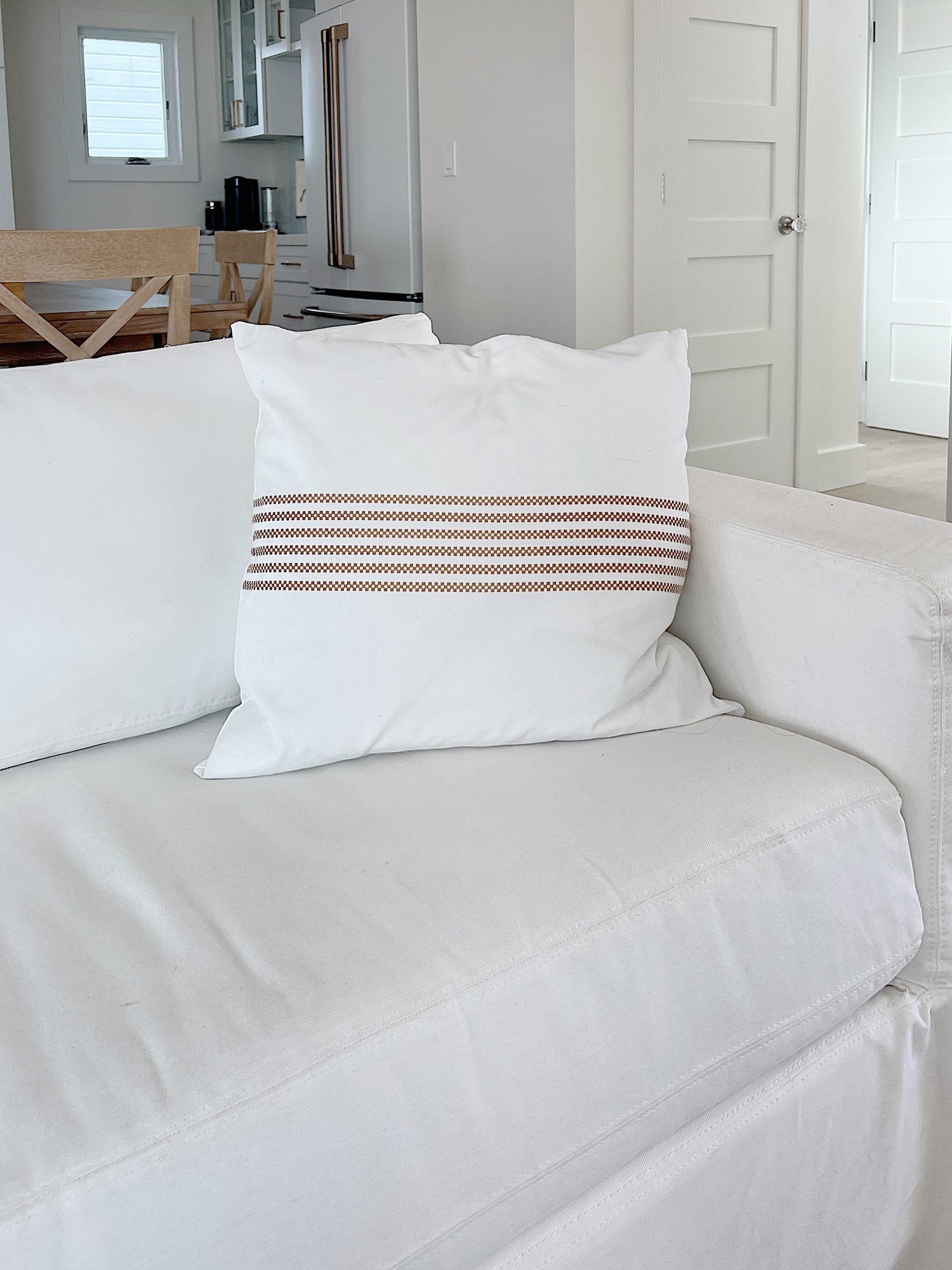 white and tan striped pillow sitting on a white couch