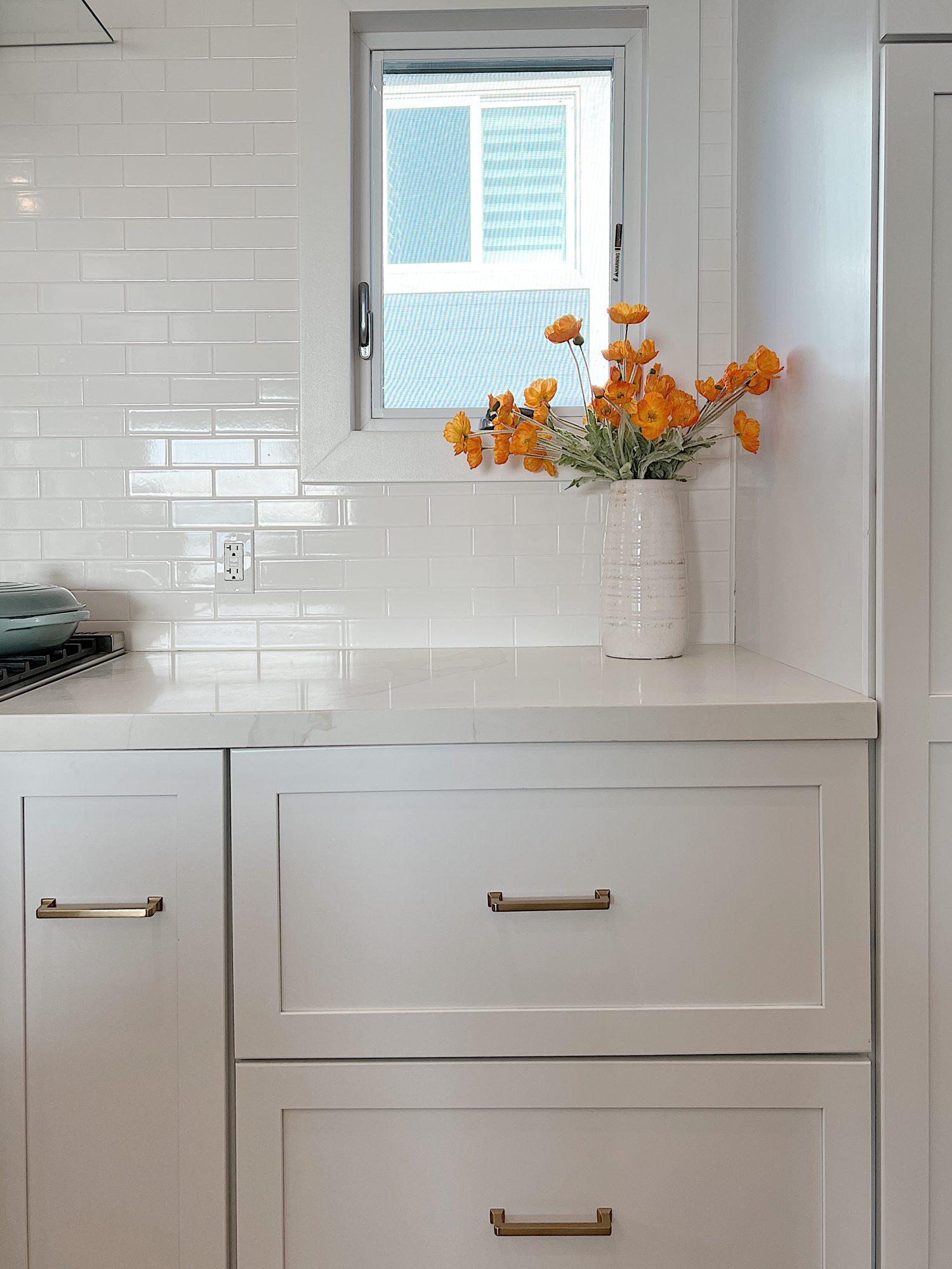 white beach house kitchen with island, countertops, white cabinets, and new lighting.