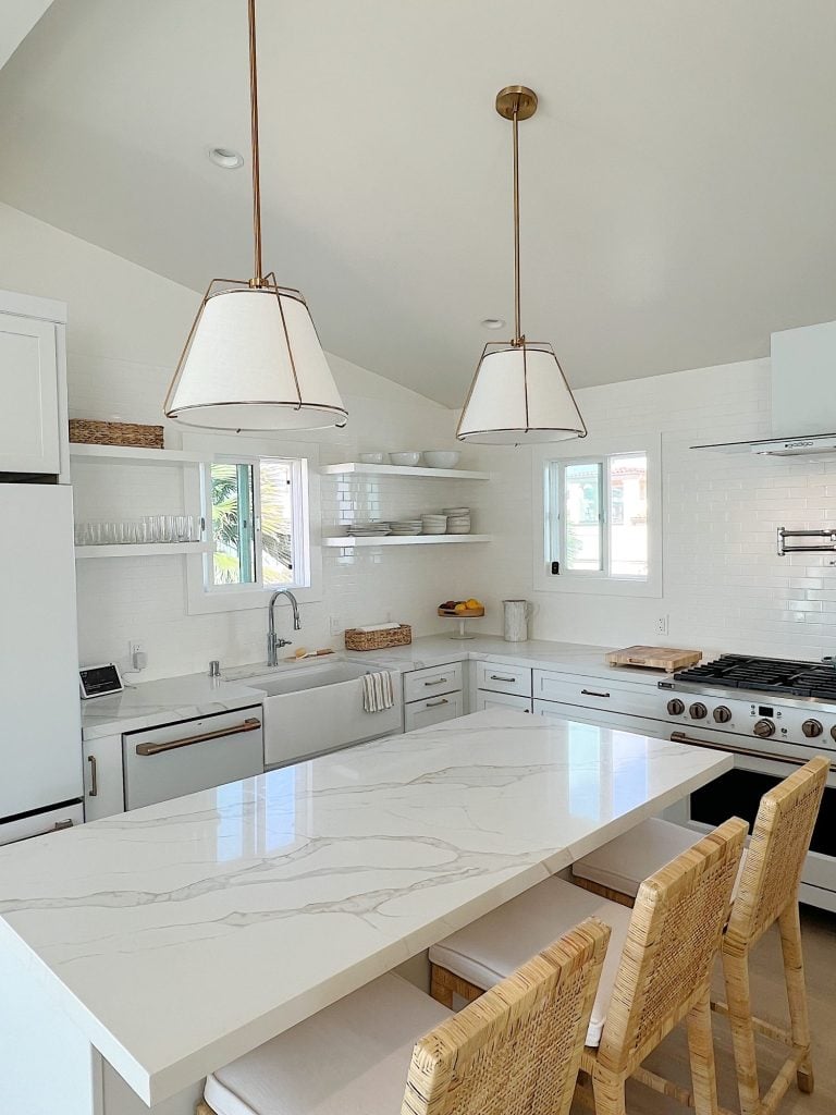 white beach house kitchen with island, countertops, white cabinets, and new lighting.