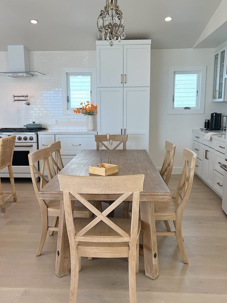Wood kitchen table and chairs in a white kitchen with white cabinets and appliances
