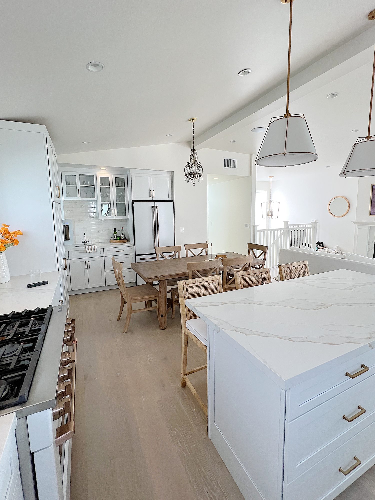 white beach house kitchen with island, countertops, white cabinets, and new lighting.