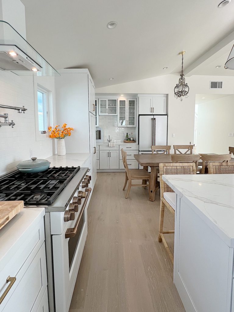 white beach house kitchen with island, countertops, white cabinets, and new lighting.