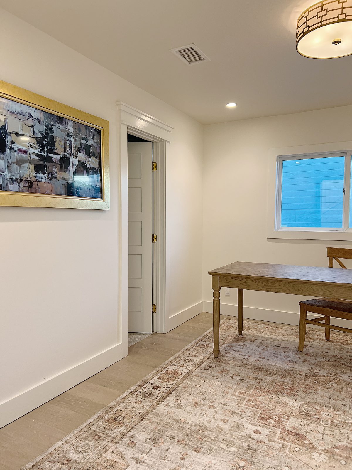 Office and fifth bedroom at the beach house with window, new rug, wood desk and chair, frame TV, and sleeper sofa.
