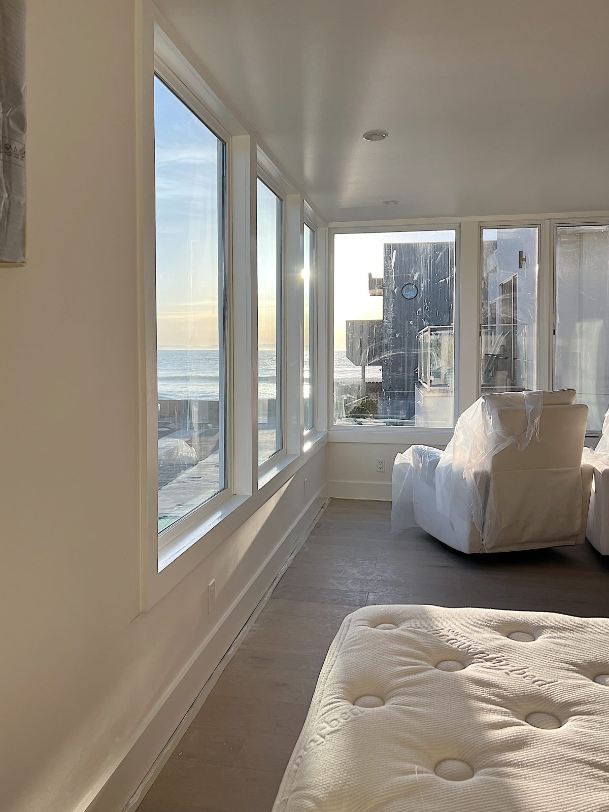 Newly remodeled primary bedroom with gorgoes ocean view, new wood floors, white glider chairs and king sized bed.