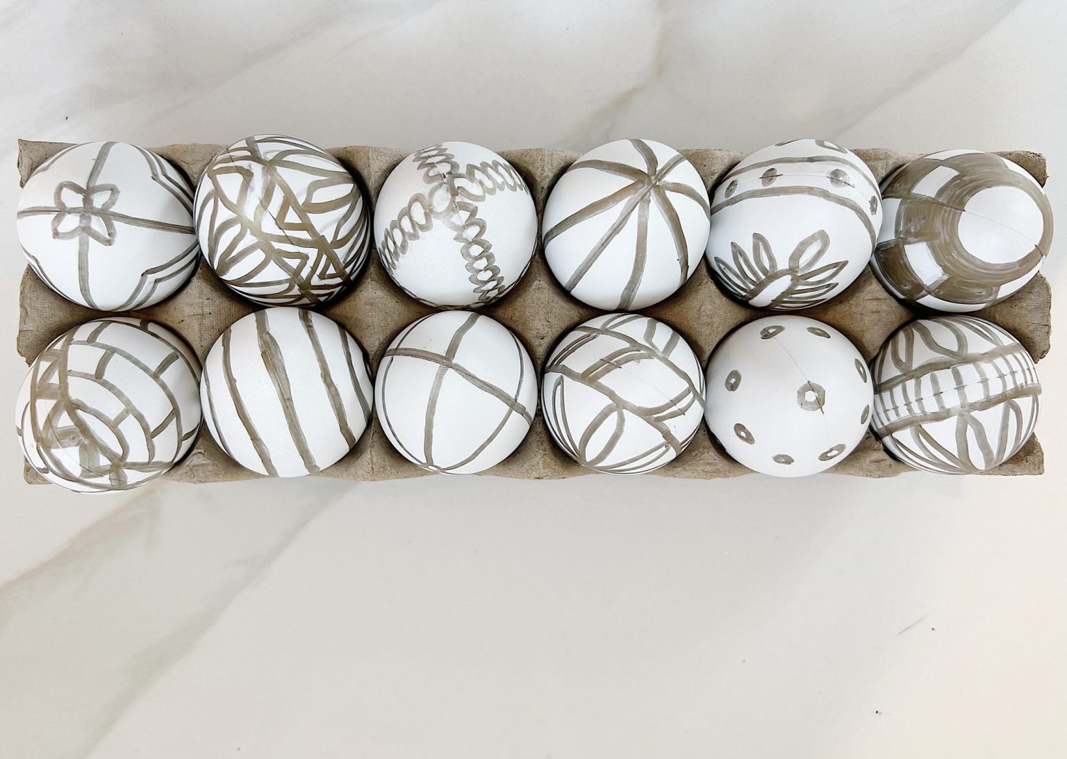 White Easter eggs painted with a copper sharpie pen and placed in an egg carton