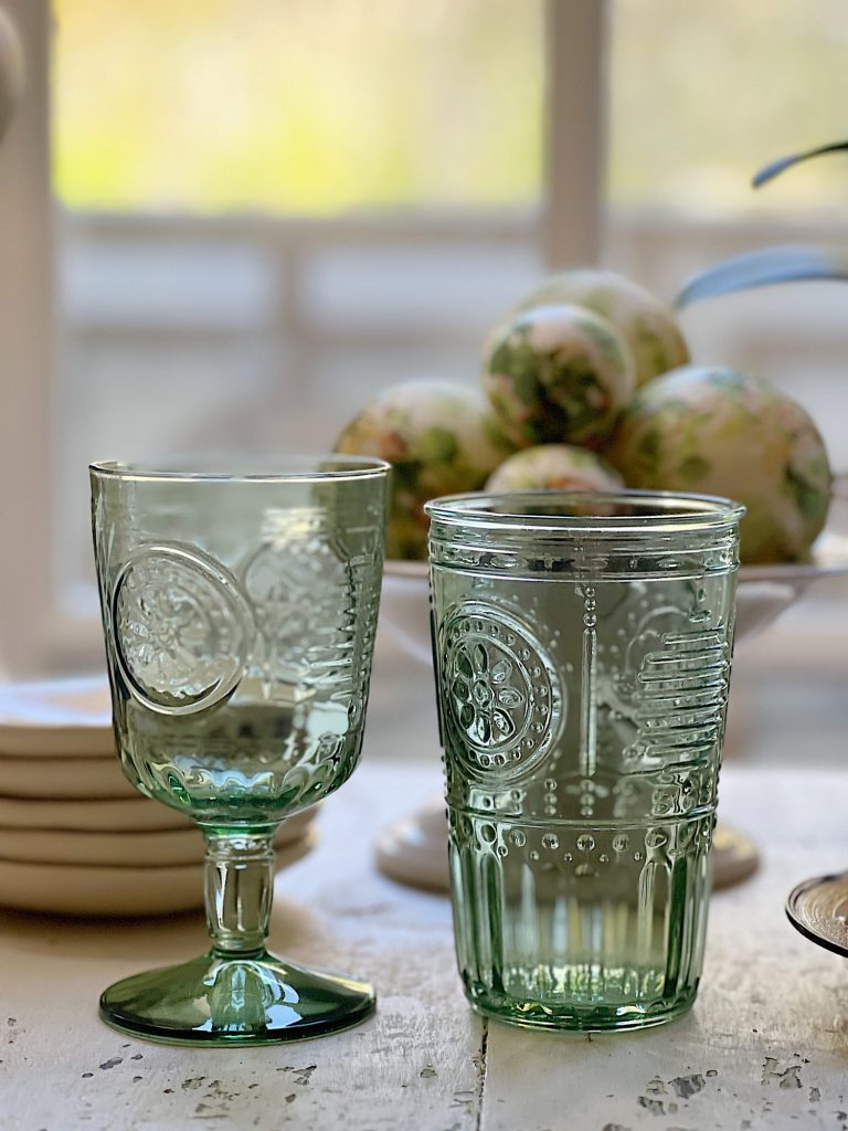 two green glasses.one is a wine goblet and the other is a highball glass.