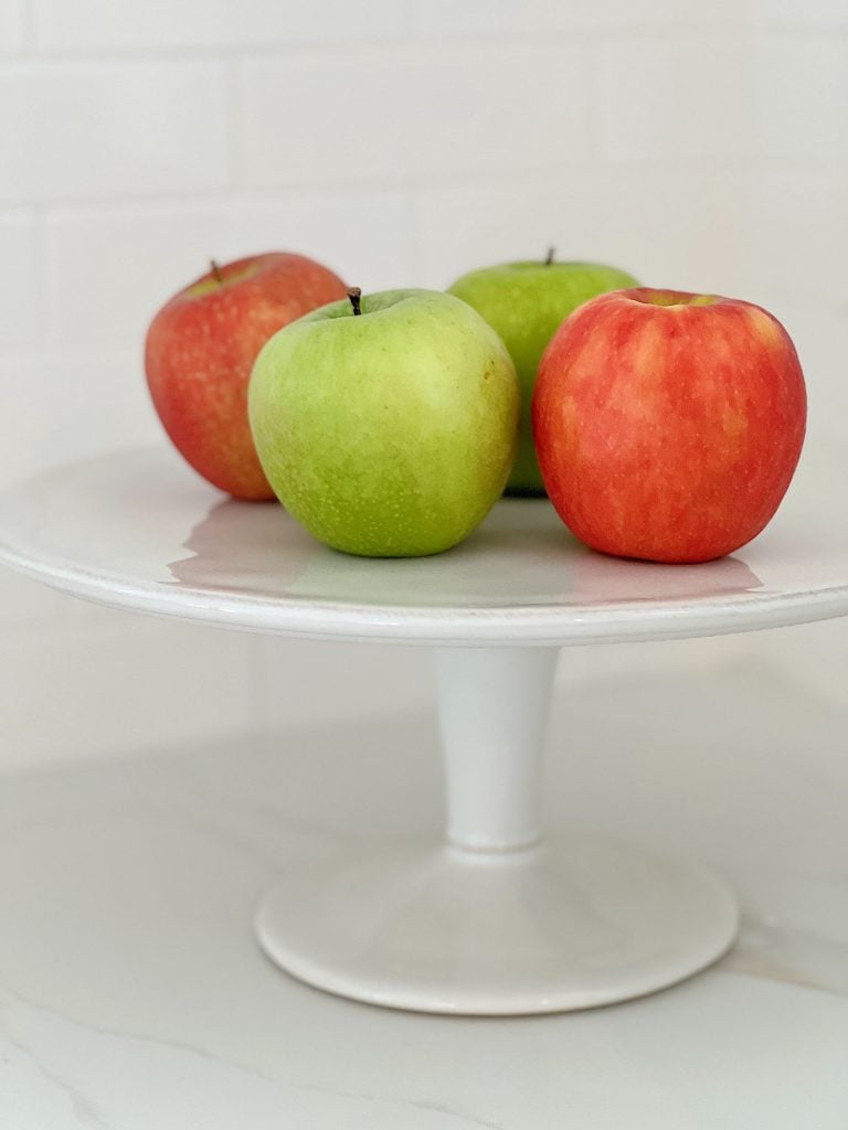 white cake stand with red and white apples on top