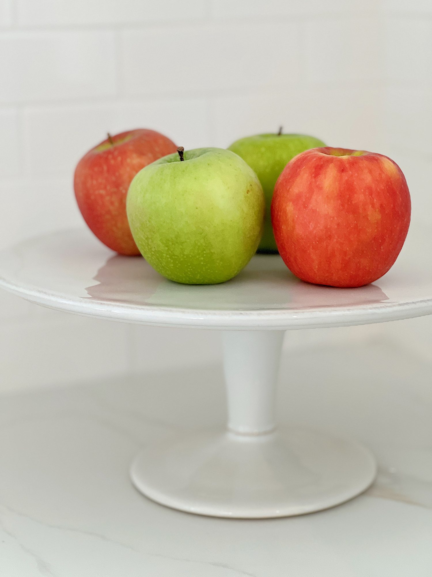 white cake stand with red and white apples on top