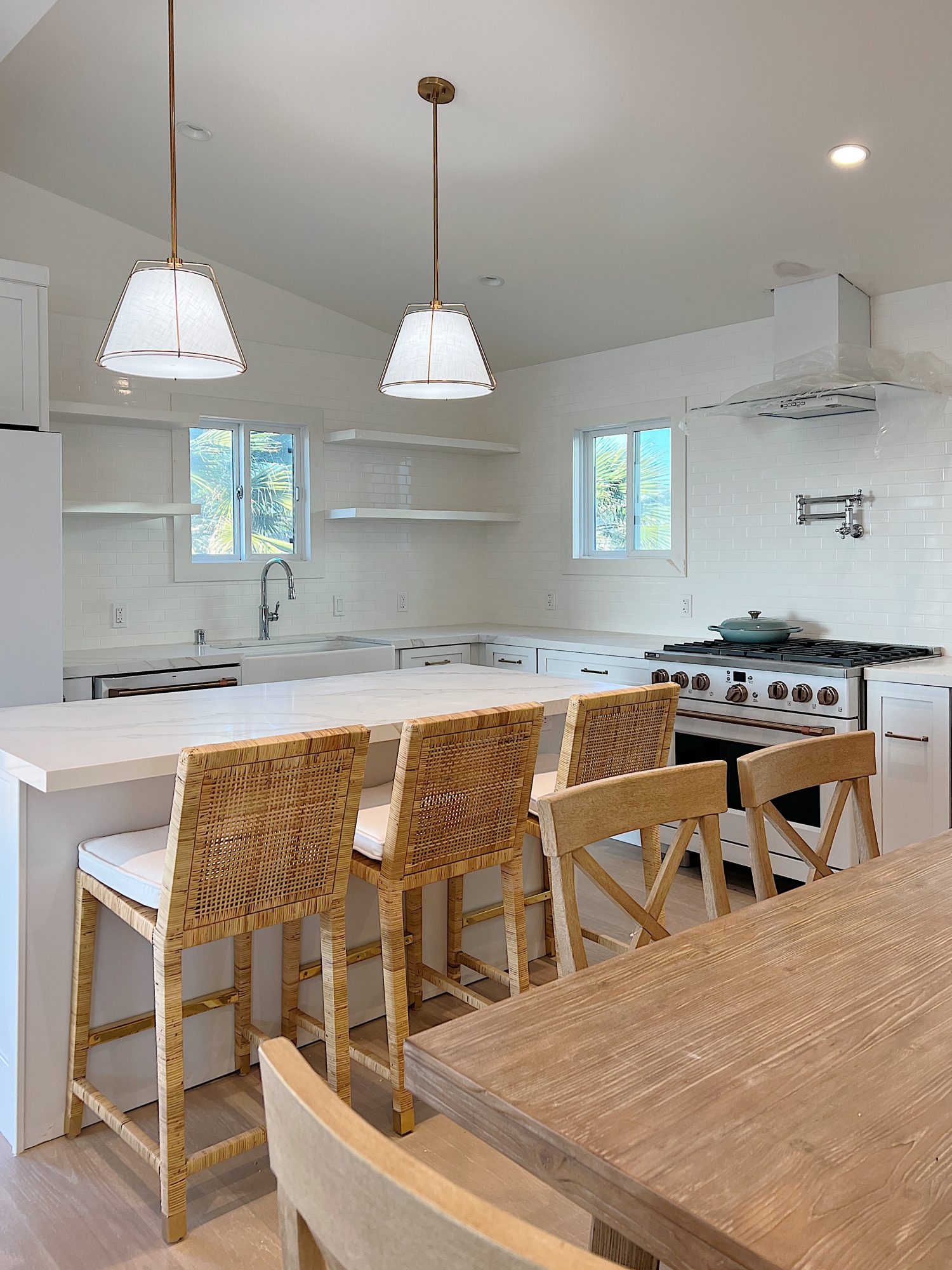 New beach house kitchen. White kitchen with white tile, quarts island, appliances, wood table and white cabinets.